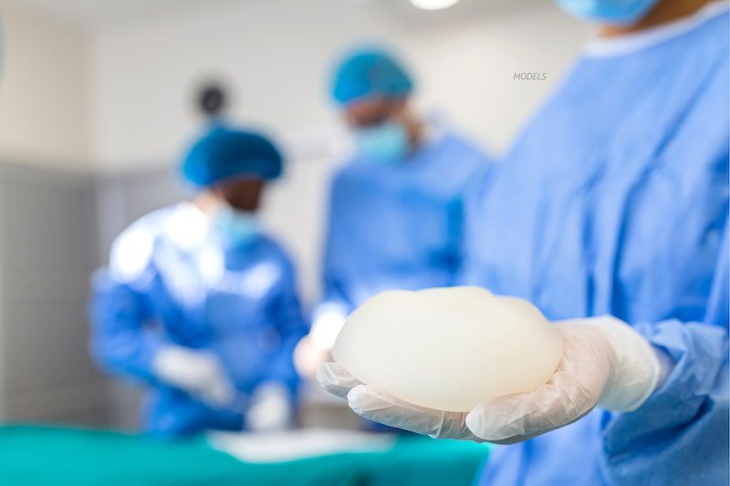 Surgeon holding a breast implant in an operating room.